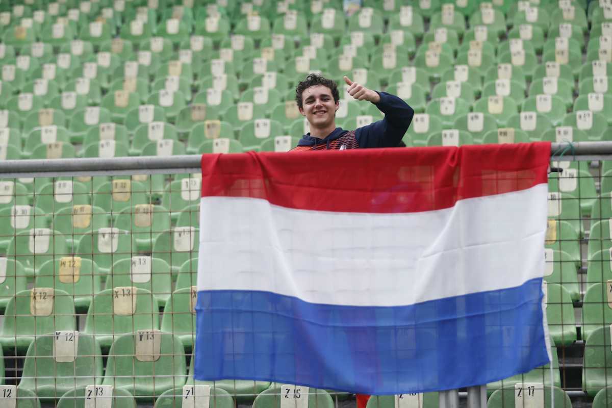 A Netherlands fan, with a flag in front, poses happily