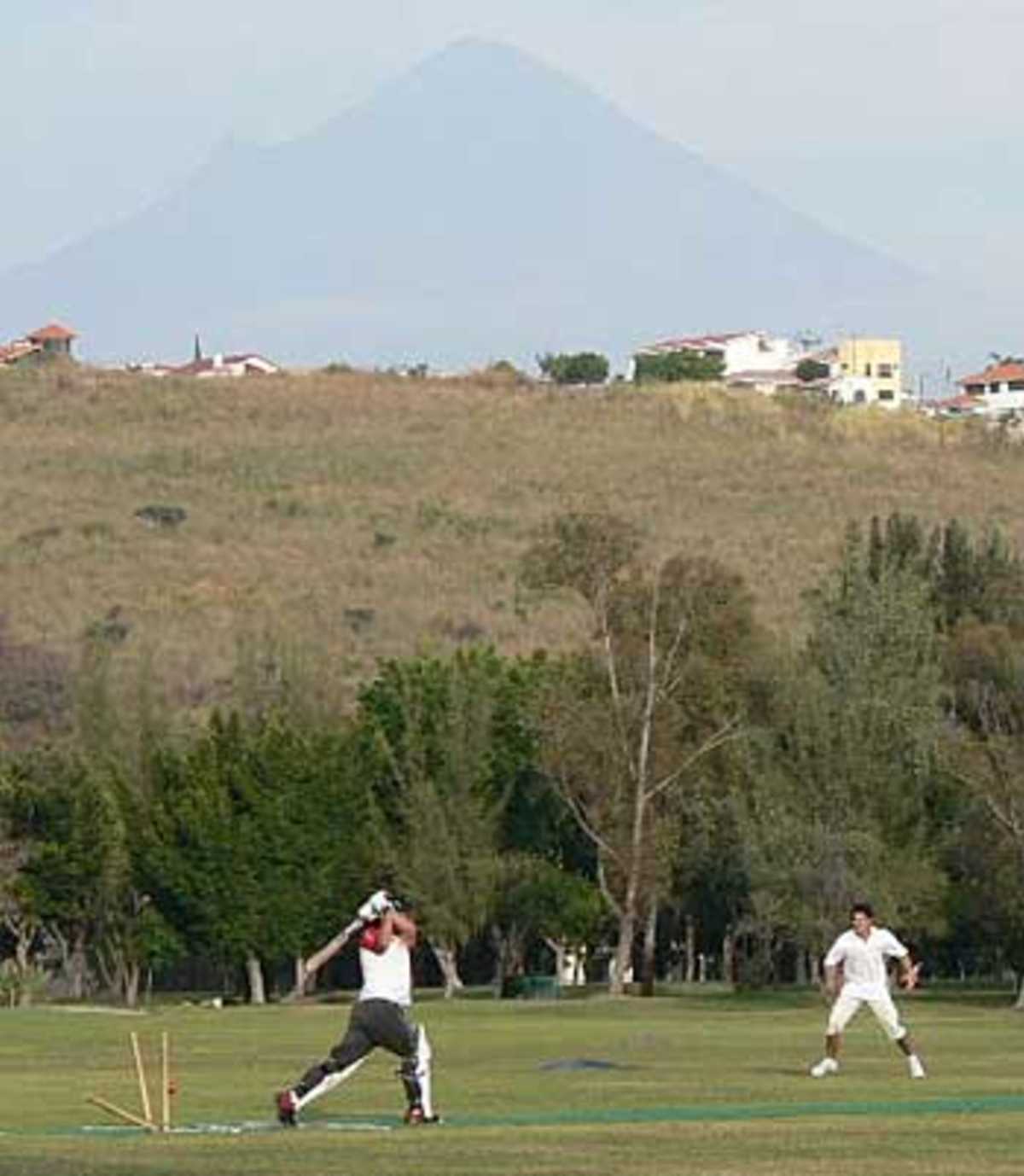 Cricket in Mexico in the town of Oaxtepec with a volcano, Volcan Popocatepet, smouldering in the background