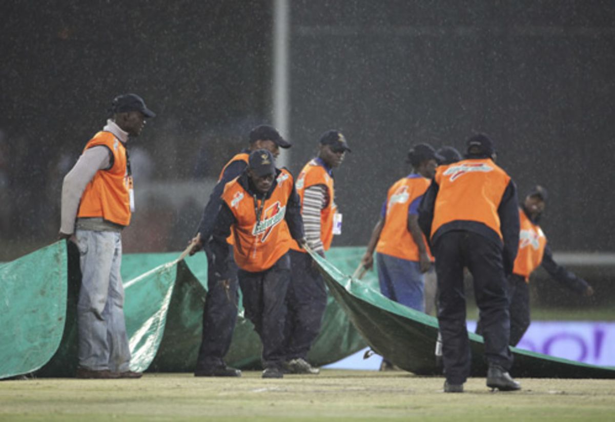 The groundstaff struggle to get the covers in place in the pouring rain