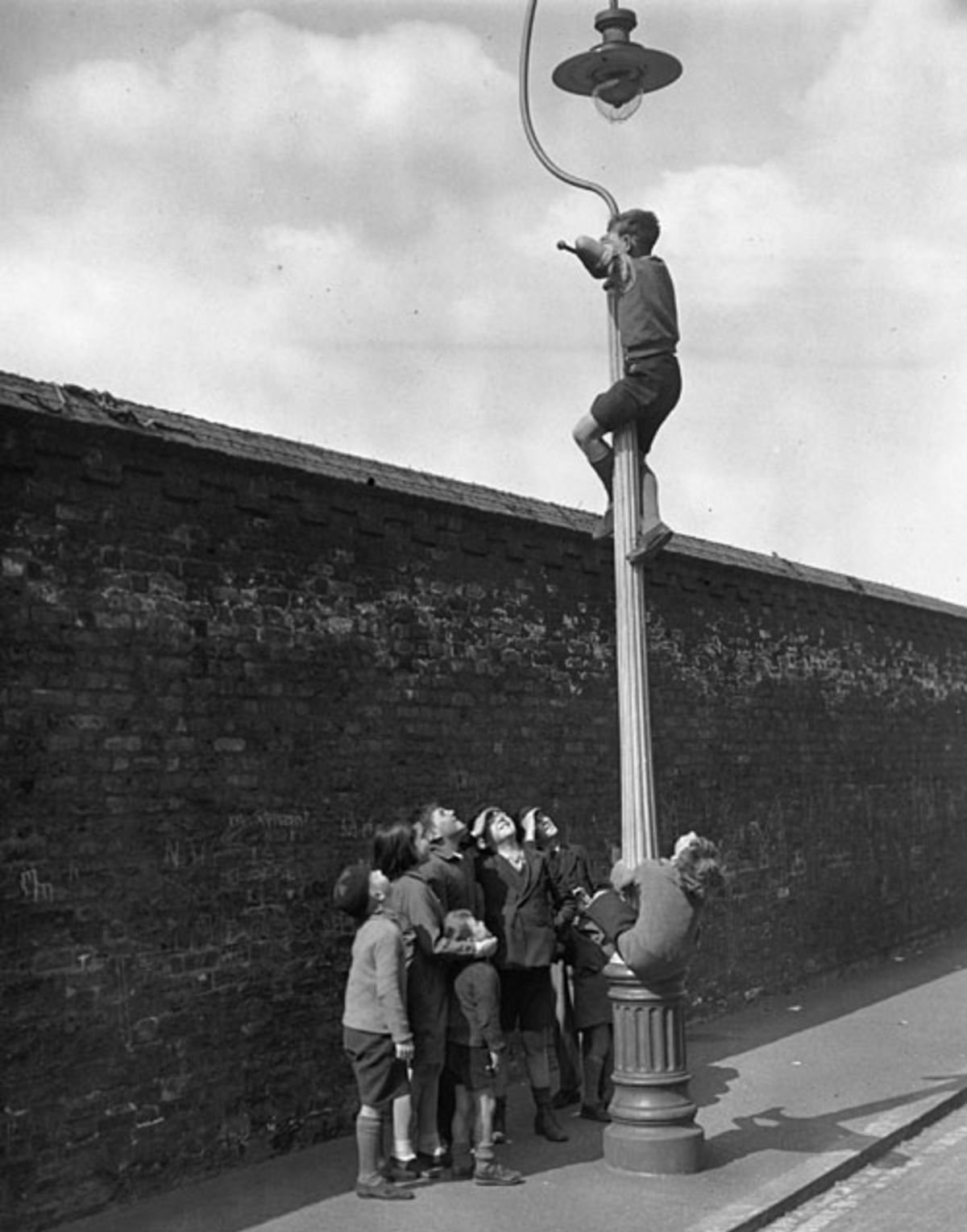 A boy watches from the top of a lamppost, while his friends wait below for a commentary, Surrey v Australians, 1st day, The Oval, May 21, 1938