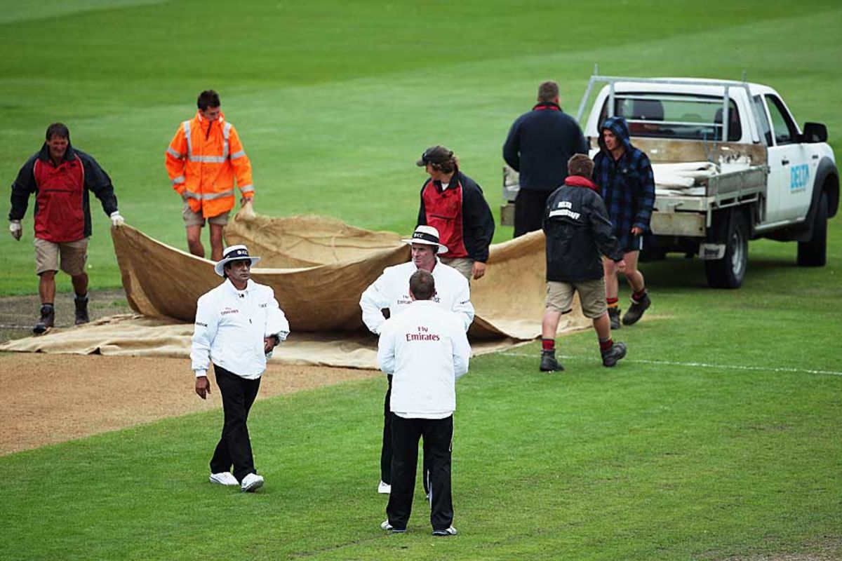 The umpires in consultation after the covers are brought on to the