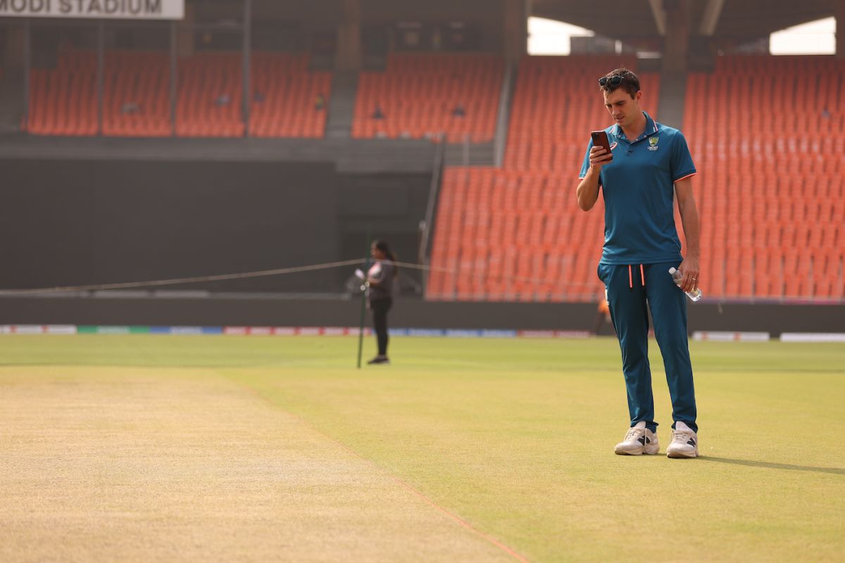 Pat Cummins looks at his mobile phone while inspecting the pitch |  ESPNcricinfo.com