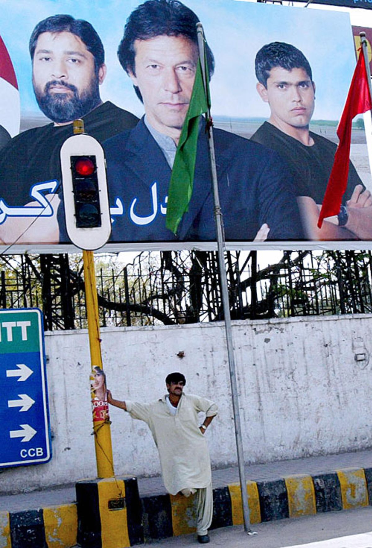 A pedestrian in Islamabad stands beneath a billboard showing Inzamam-ul-Haq, Imran Khan and Kamran Akmal, Islamabad, March 29, 2007