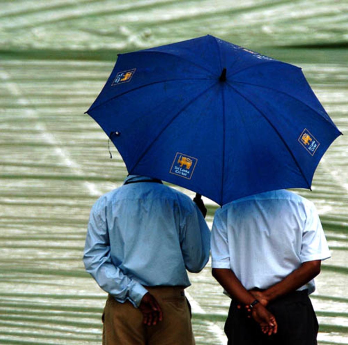 cricket-officials-shelter-themselves-under-an-umbrella-after-rain-interrupted-play