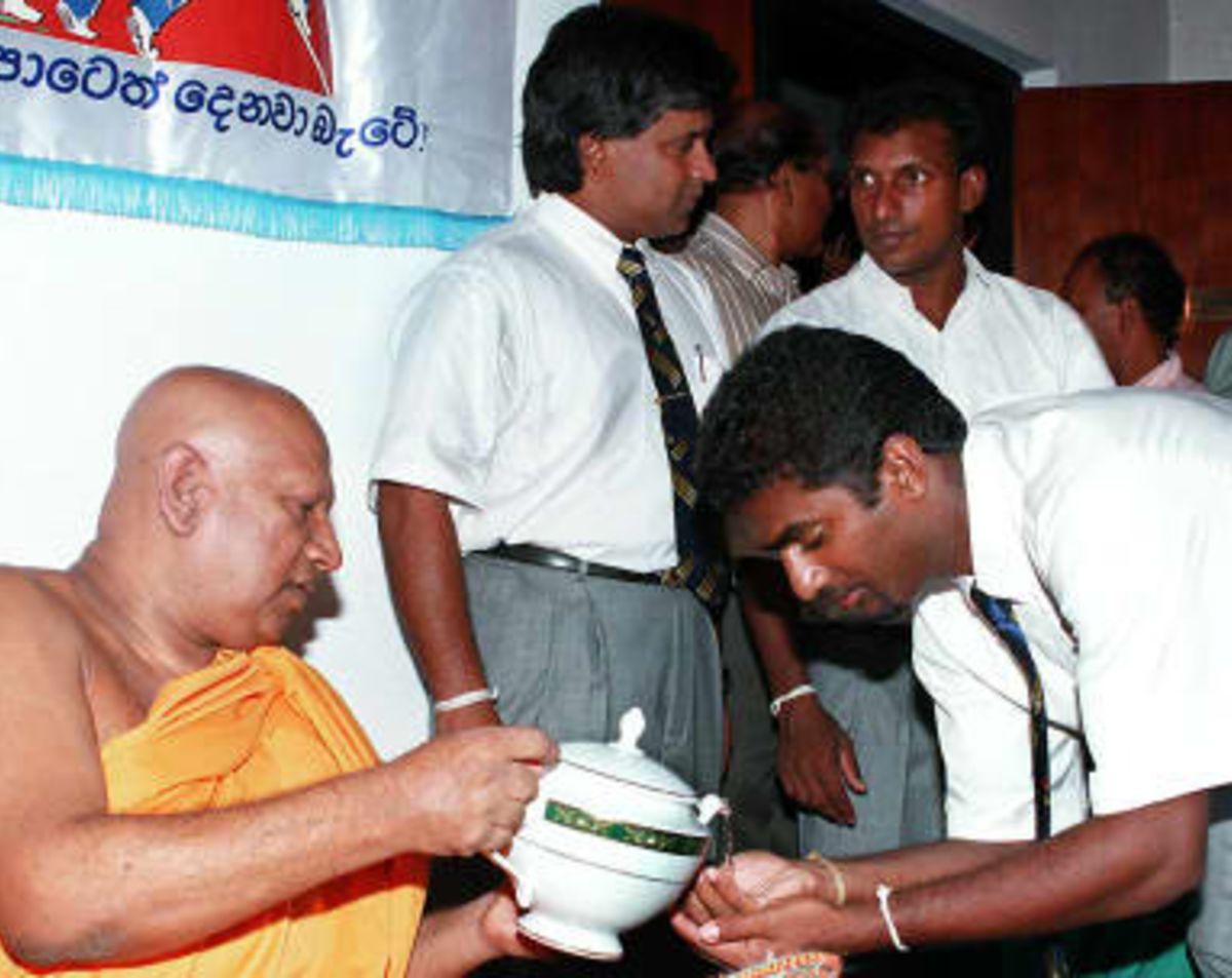 Buddhist monk Bellanvila Wimalaratne gives blessed holy water to Sri Lanka's star leg spinner Muttiah Muralitharan while skipper Arjuna Ranatunga and his deputy Aravinda de Silva have a conversation, just before the team leaves, on 24 April 1999 in Colombo, for England to take part in the Cricket World Cup.