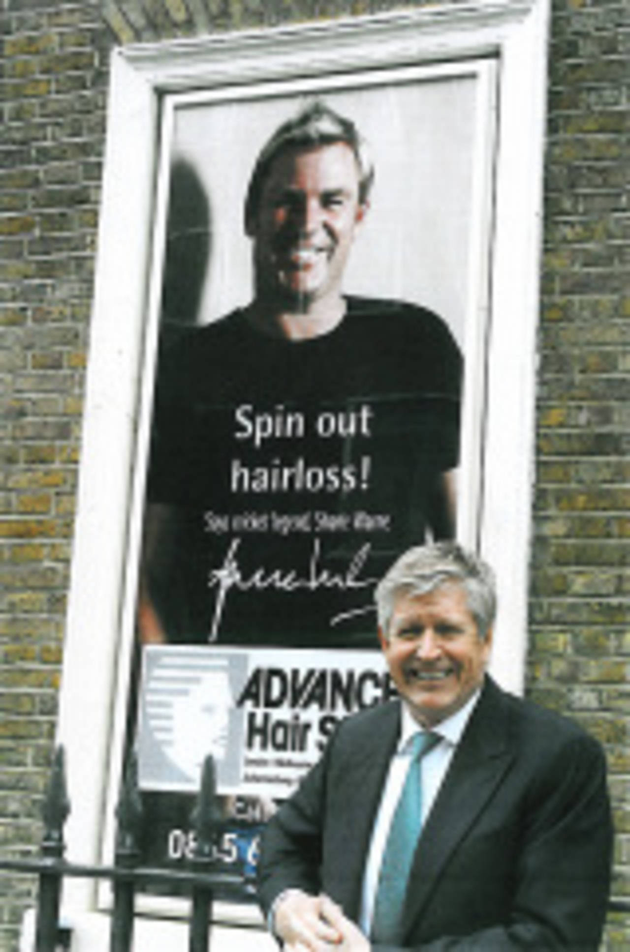 Carl Howell, chairman of Advanced Hair Studios, in front of a poster of Shane Warne, Camden, London, June 29, 2009