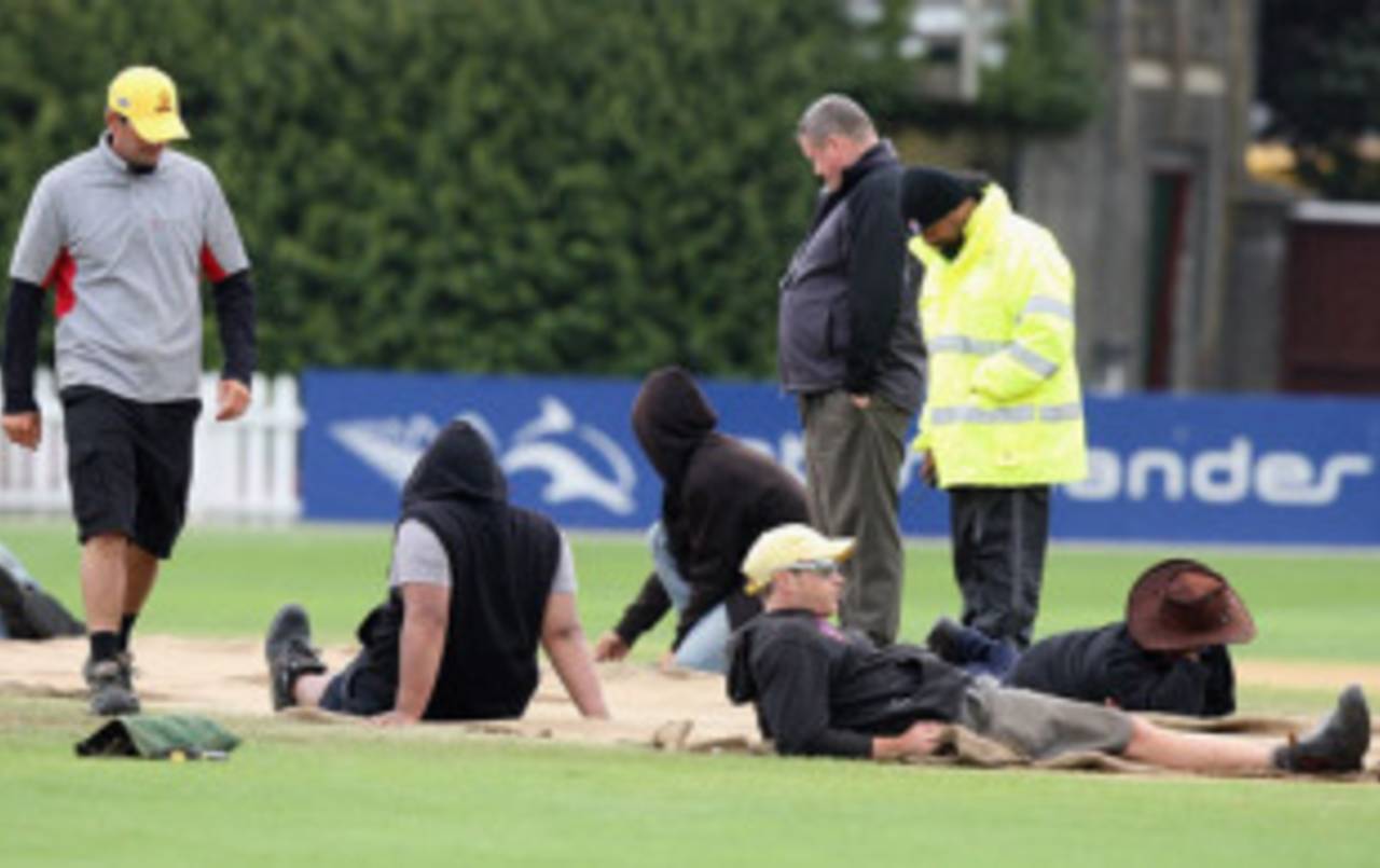 Time for a lie down: The Wellington groundstaff sit on the covers to stop them blowing away&nbsp;&nbsp;&bull;&nbsp;&nbsp;Getty Images
