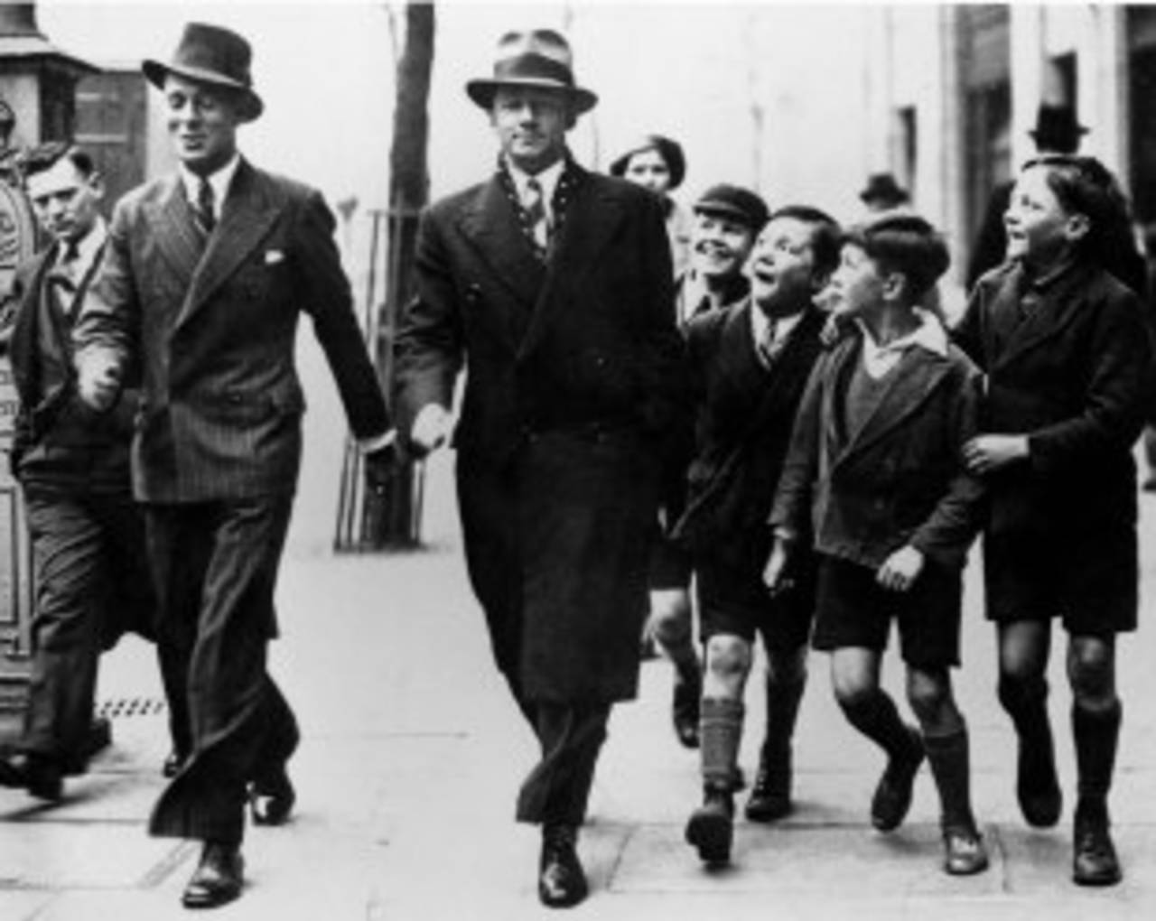 Don Bradman walks down Strand with a group of children following him, 1938