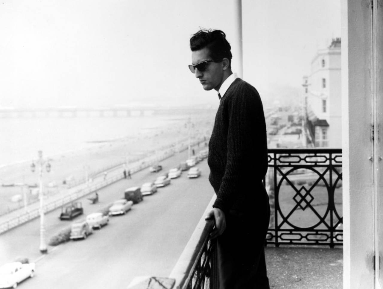 Mansur Ali Khan Pataudi stands on a balcony overlooking an esplanade and beach, 1961
