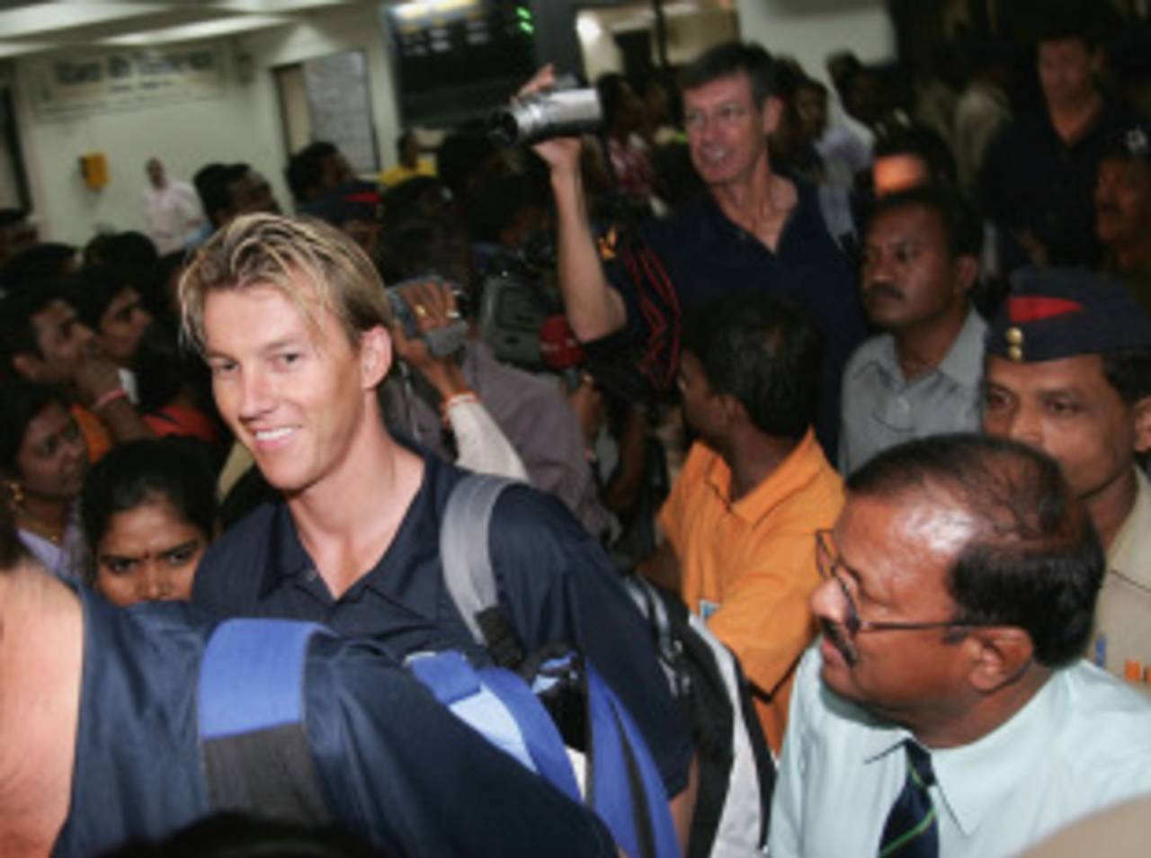 Brett Lee and John Buchanan walk through a crowd at the Nagpur airport, October 23, 2004