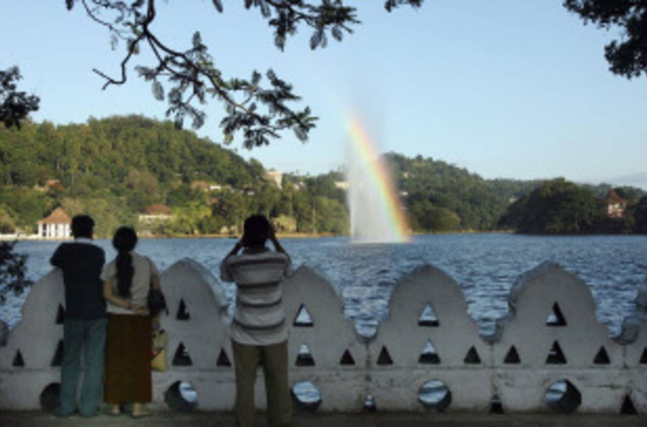 A man takes a photograph of a rainbow over the Kandy Lake, Kandy, November 30, 2007