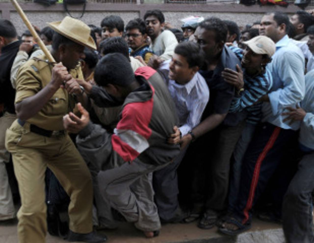 A policeman tries to control the crowd after a mini-stampede broke out among people queuing up for tickets for the India-England game outside the M Chinnaswamy stadium, Bangalore, February 24, 2011