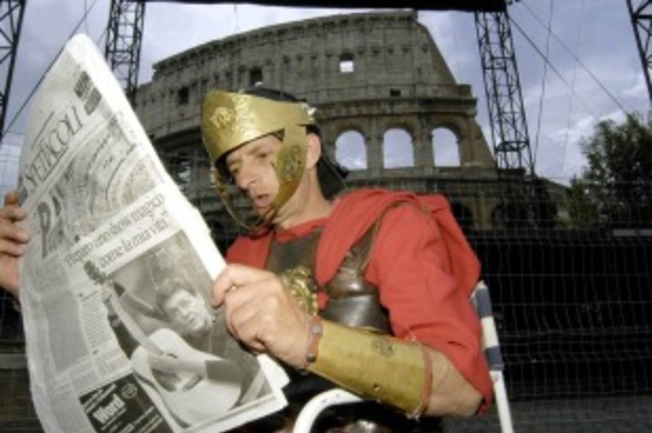 A man dressed as a gladiator reads a newspaper near the Colosseum, Rome, May 9, 2003