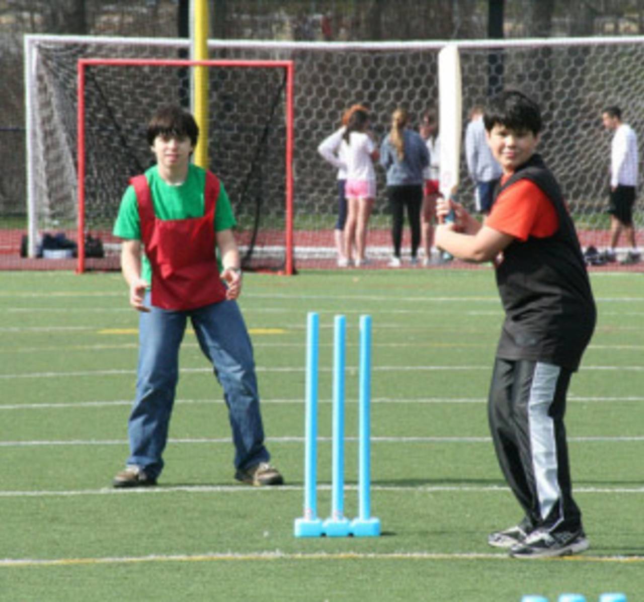 American school kids take a baseball stance at a cricket game