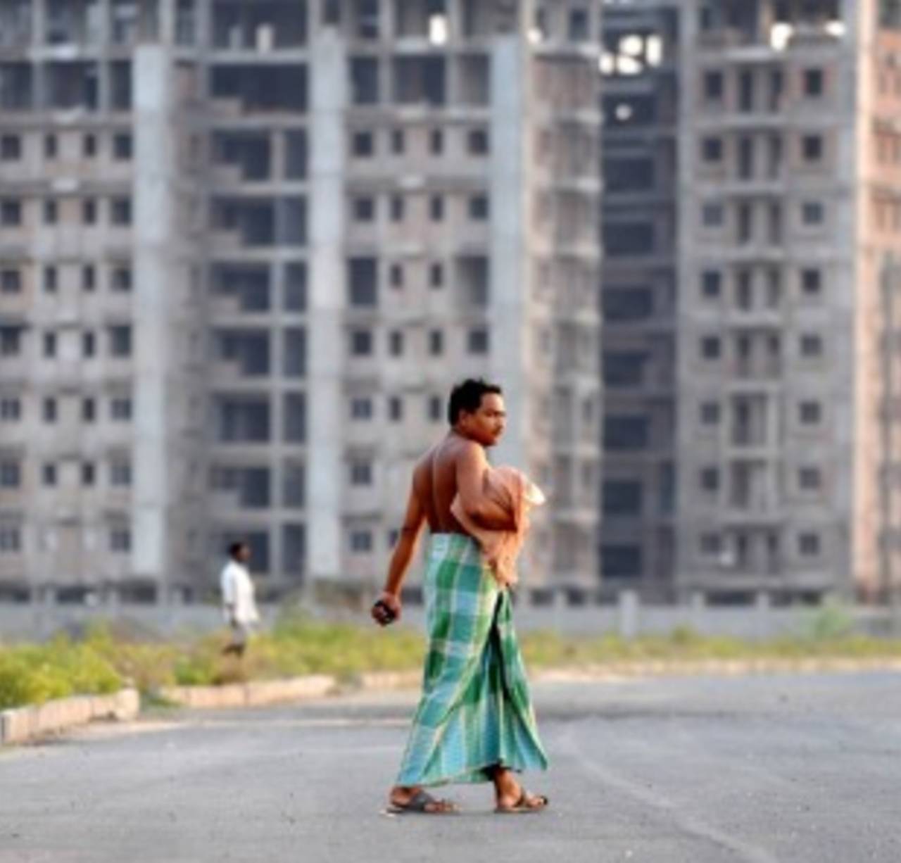 An Indian villager crosses a road passing new large-scale residential developments in Rajarhat, close to Kolkata