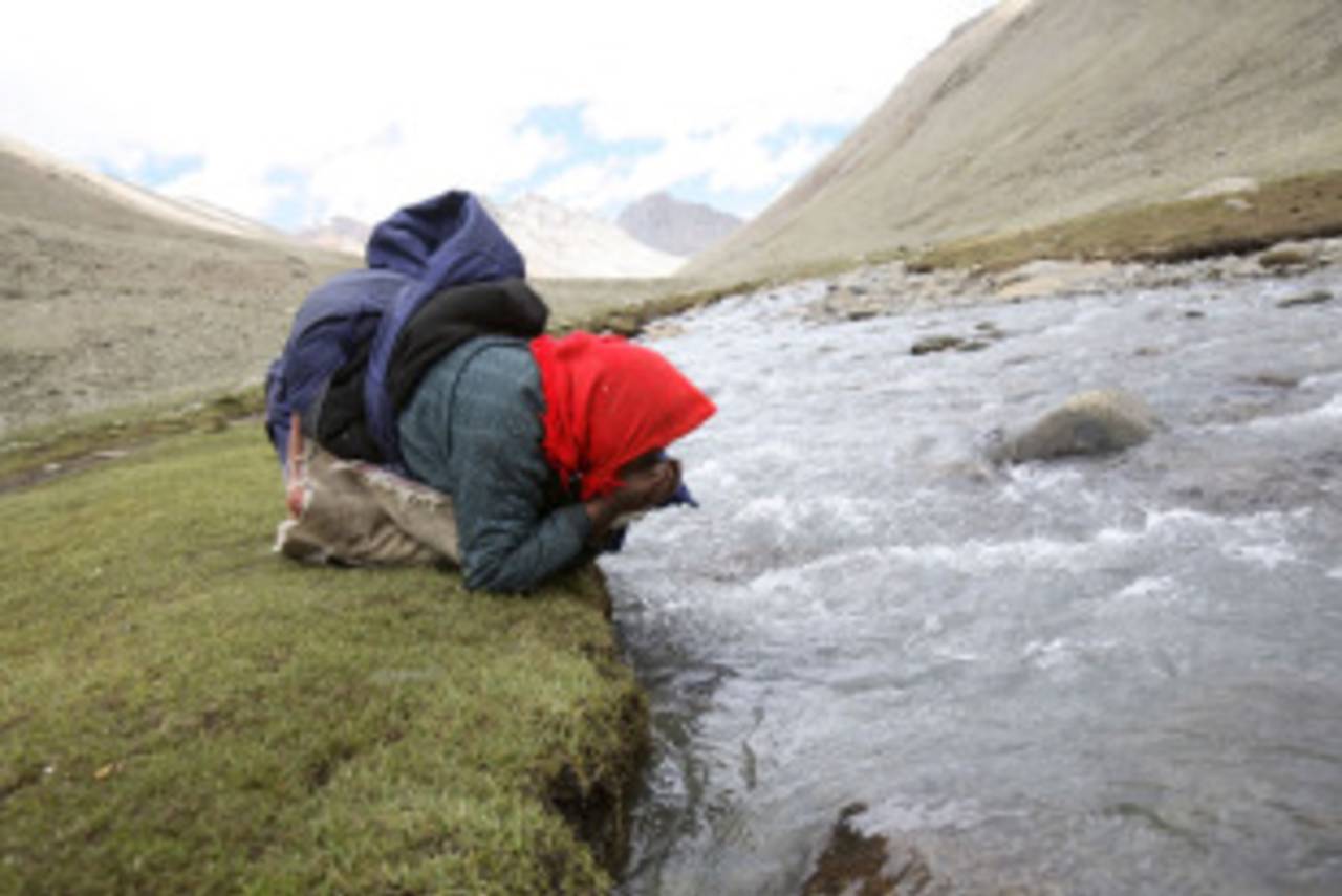A Tibetan nomad drinks water from a river at Mount Kailash, June 16, 2007