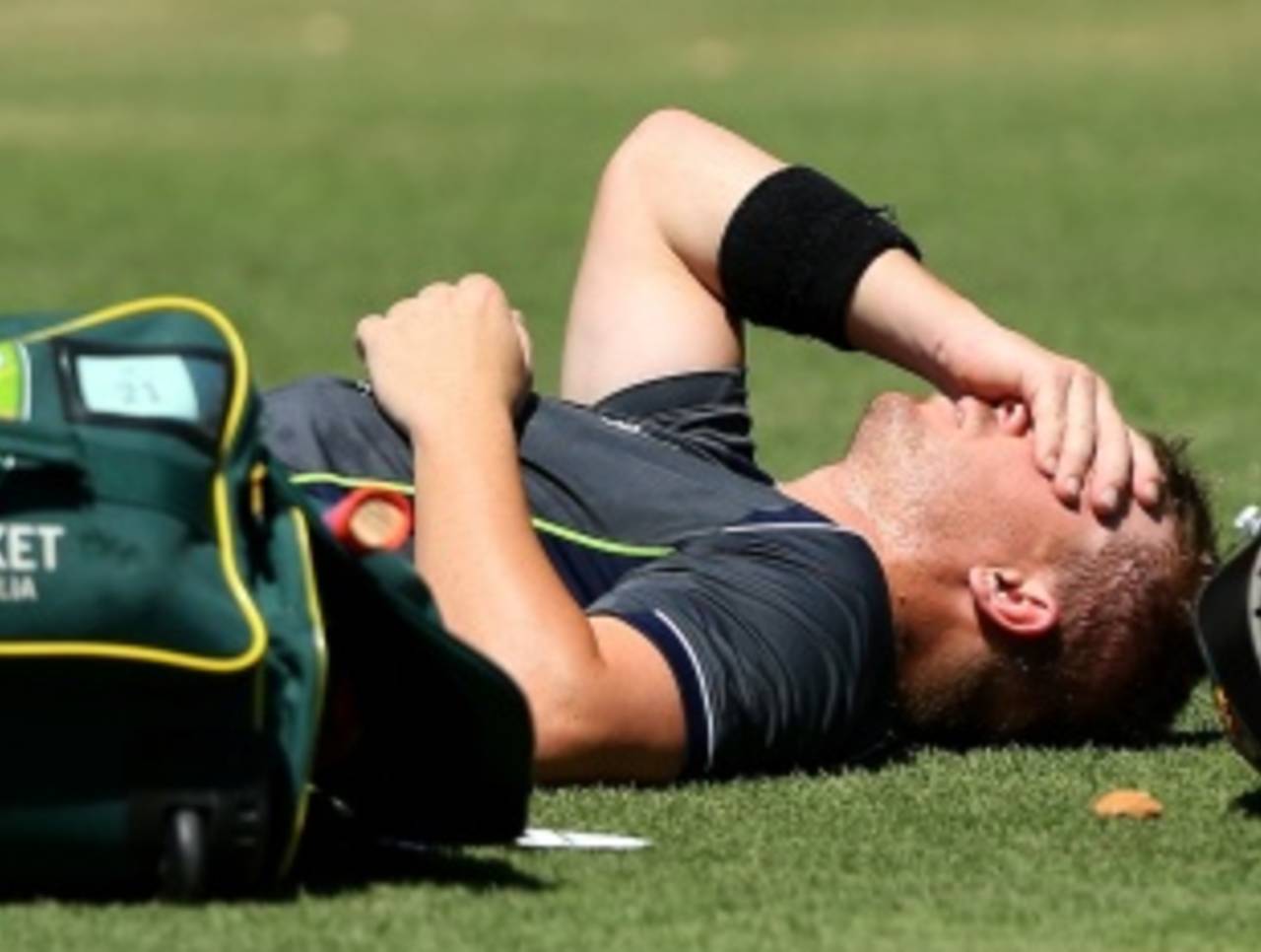 David Warner lies on the ground after getting hit on the hand while batting during a net session, Perth, January 30, 2013