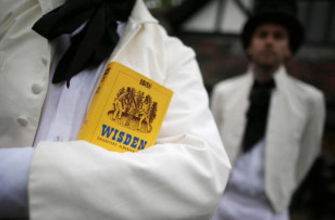A team member holds a copy of the <i>Wisden Cricketers' Almanack</i> during a Victorian cricket match, Vincent Square, London, May 29, 2013