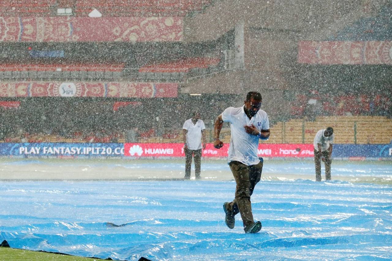 A member of the groundstaff tries to escape the deluge. Royal Challengers Bangalore v Kolkata Knight Riders, IPL 2015, Bangalore, May 2, 2015