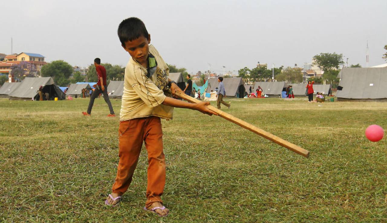 A young boy playing cricket using makeshift equipment at a relief camp for earthquake victims at Tundikhel in Kathmandu 