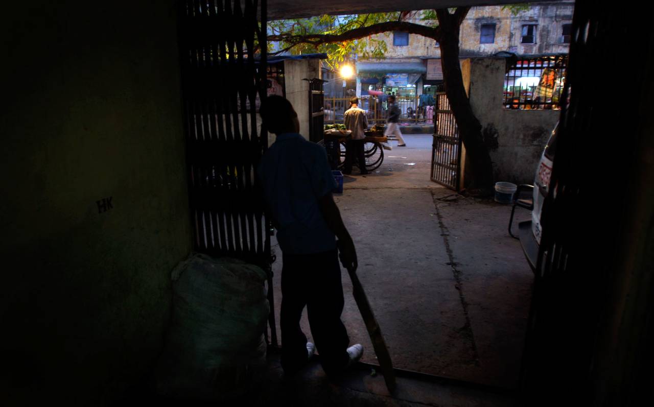 A boy stands with a bat at the foyer of a children's shelter in New Delhi, November 17, 2009