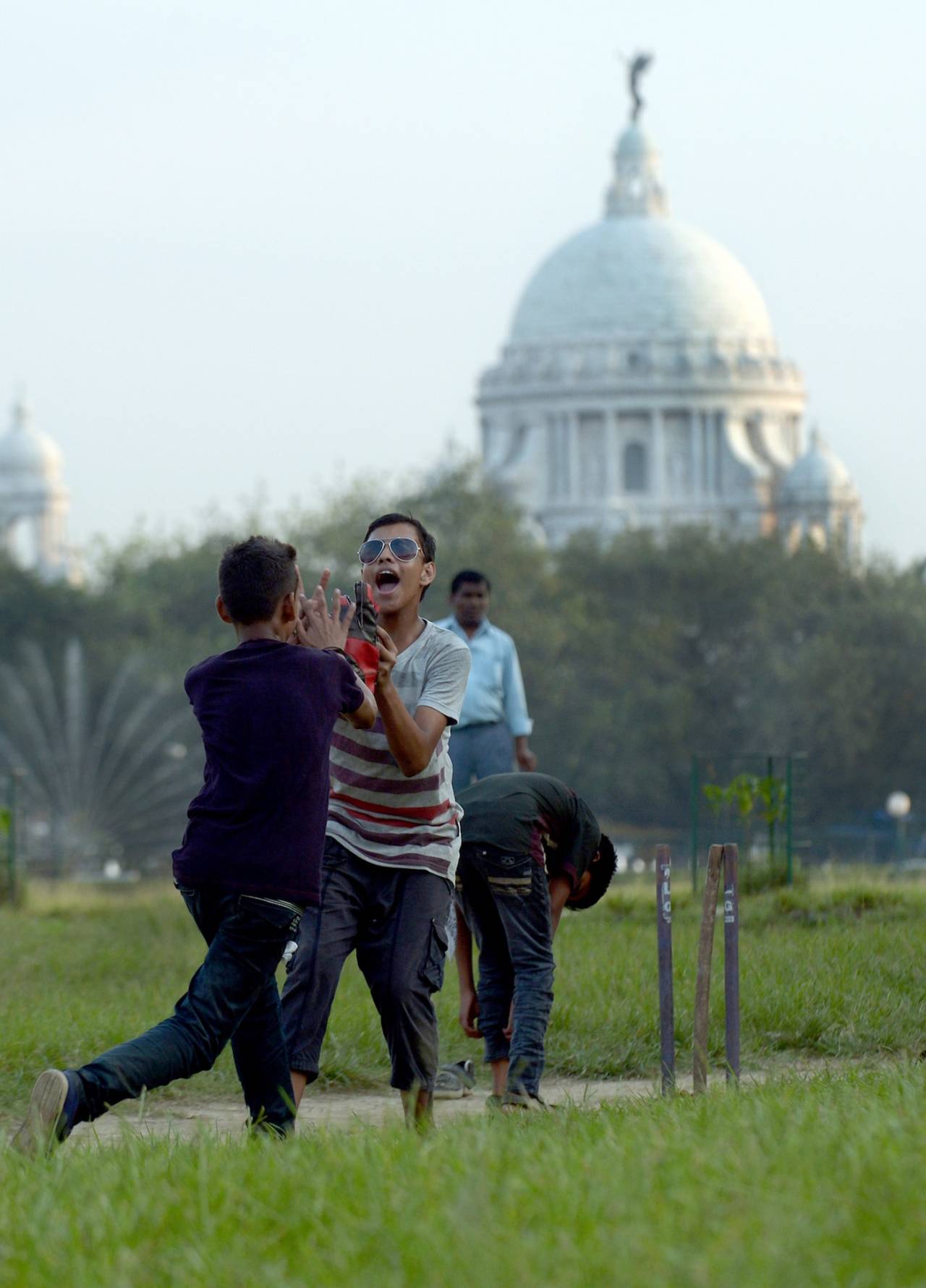 Boys celebrate a wicket at the Maidan as the Victoria Memorial looks on