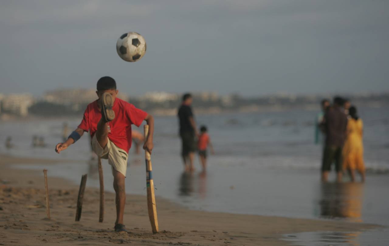 A young sportsman juggles two different games on the beaches of Mumbai