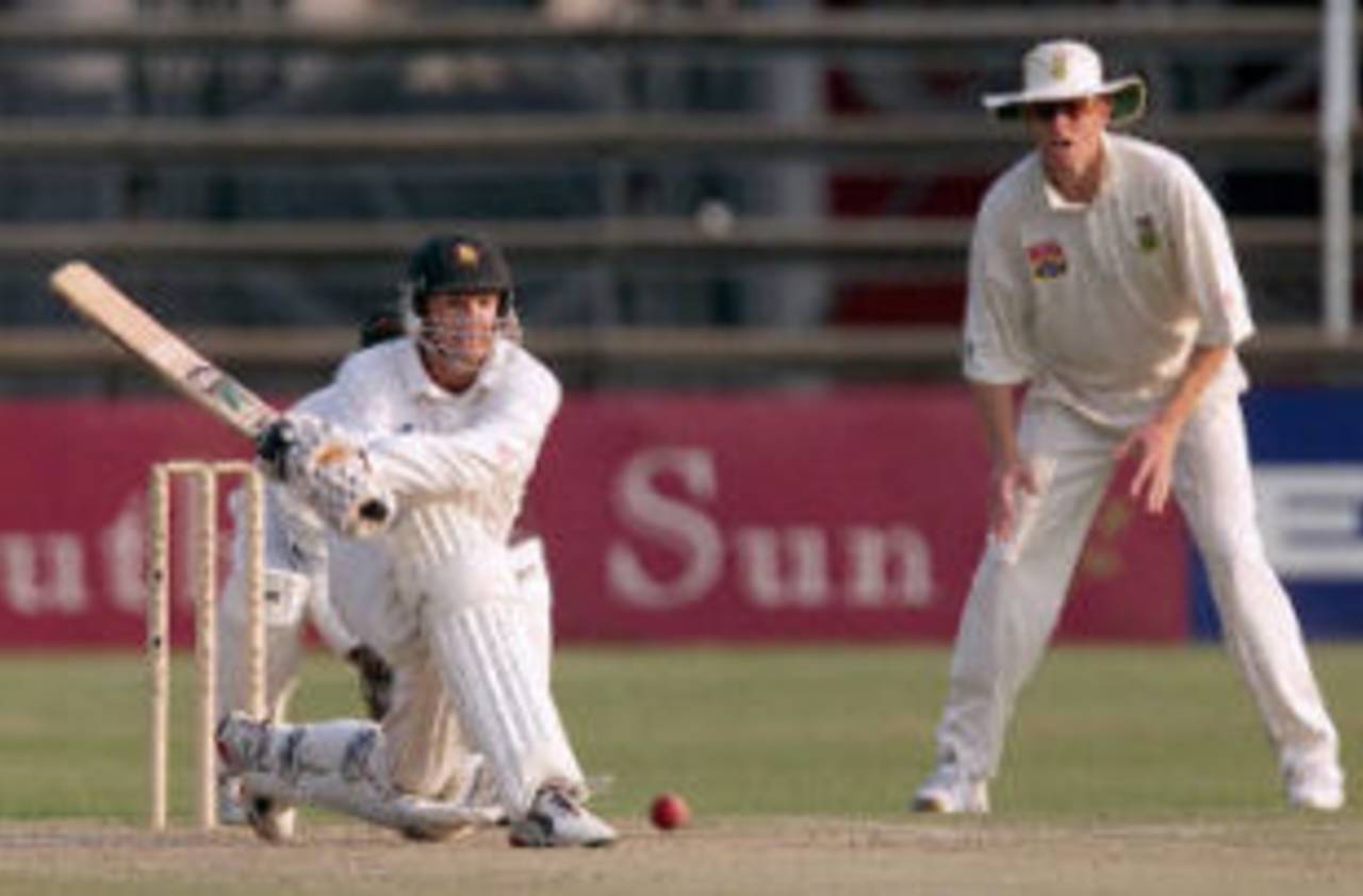 Andy Flower prepares a reverse sweep watched by Shaun Pollock, Ist Test South Africa v Zimbabwe, 7-11 September 2001, at Harare.