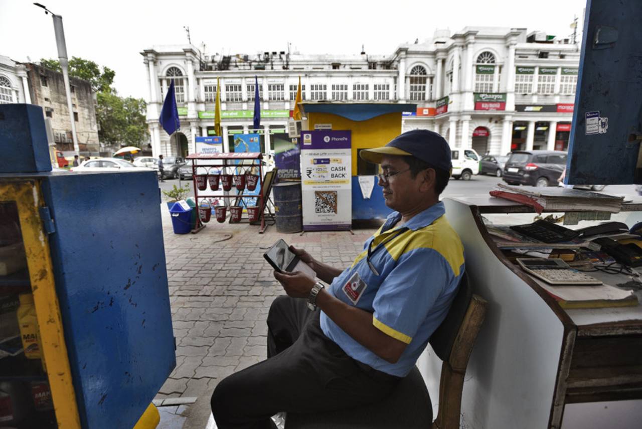 A petrol pump operator in New Delhi follows India's World Cup semi-final game against New Zealand on his mobile phone, July 9, 2019