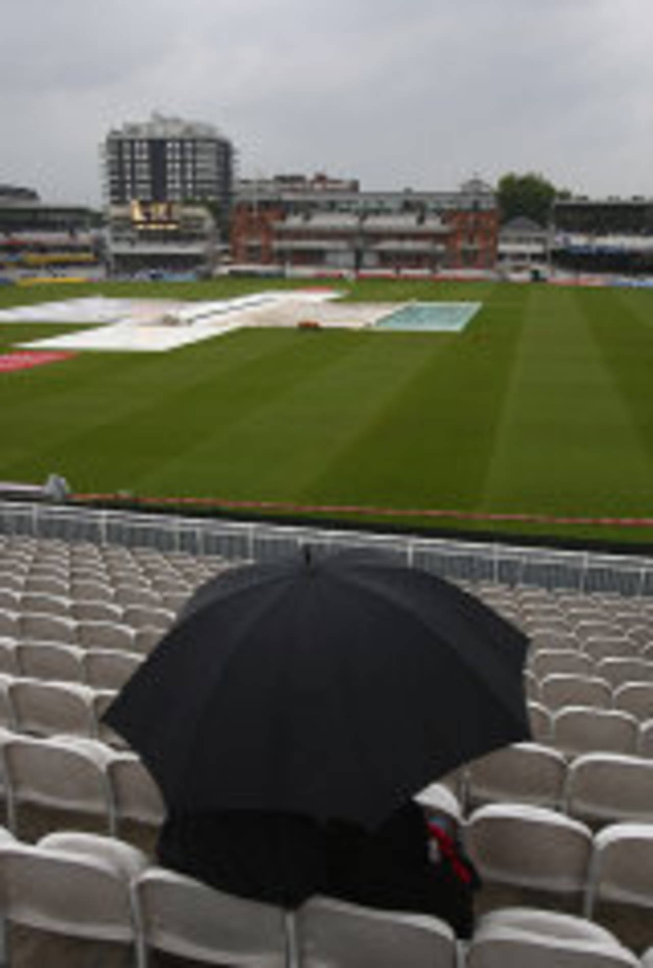 A lone fan shelters from the torrential rain under an umbrella at Lord's, England v India, 1st Test, Lord's, 2nd day, July 20, 2007
