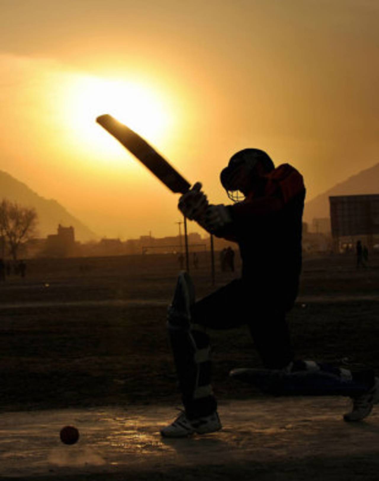 An Afghan boy plays cricket on the grounds in front of the stadium in Kabul, February 27, 2008