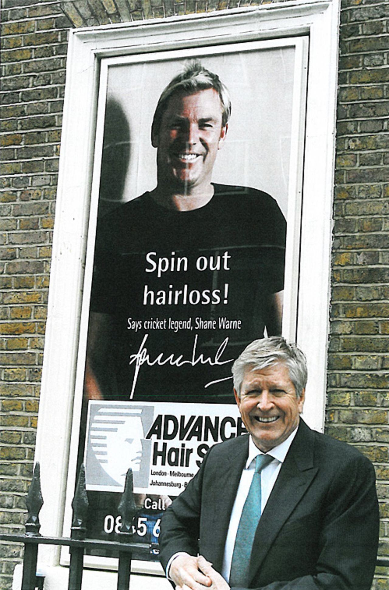 Carl Howell, chairman of Advanced Hair Studios, in front of a poster of Shane Warne, Camden, London, June 29, 2009