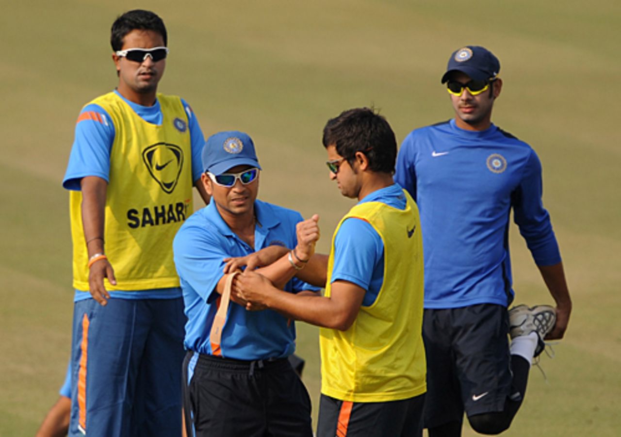 Pragyan Ojha and Manoj Tiwary look on as Sachin Tendulkar gets assistance from Suresh Raina, Kolkata, December 23, 2009