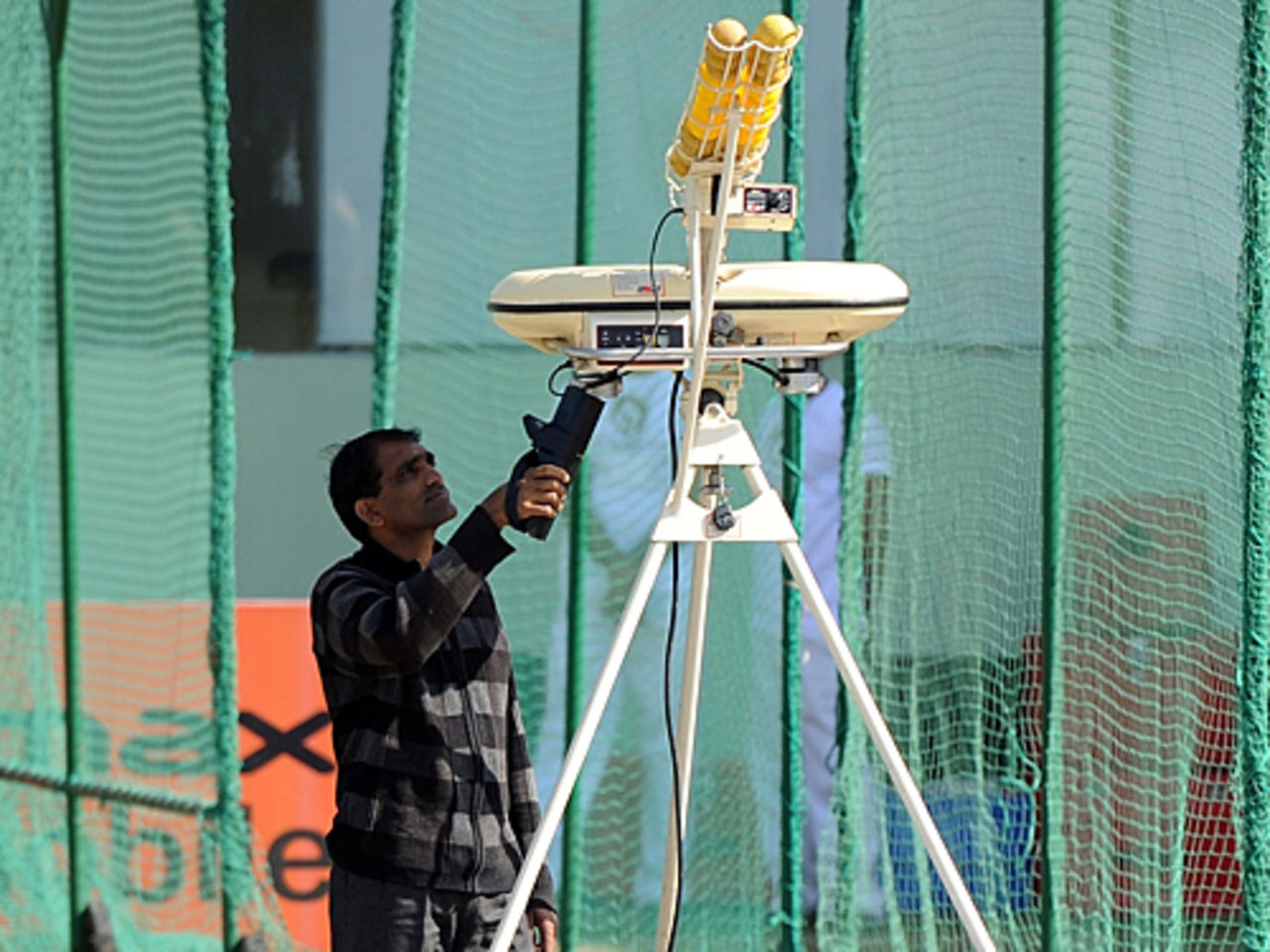 An Indian security official checks a bowling machine in the nets prior to a training session, Jaipur, February 20, 2010