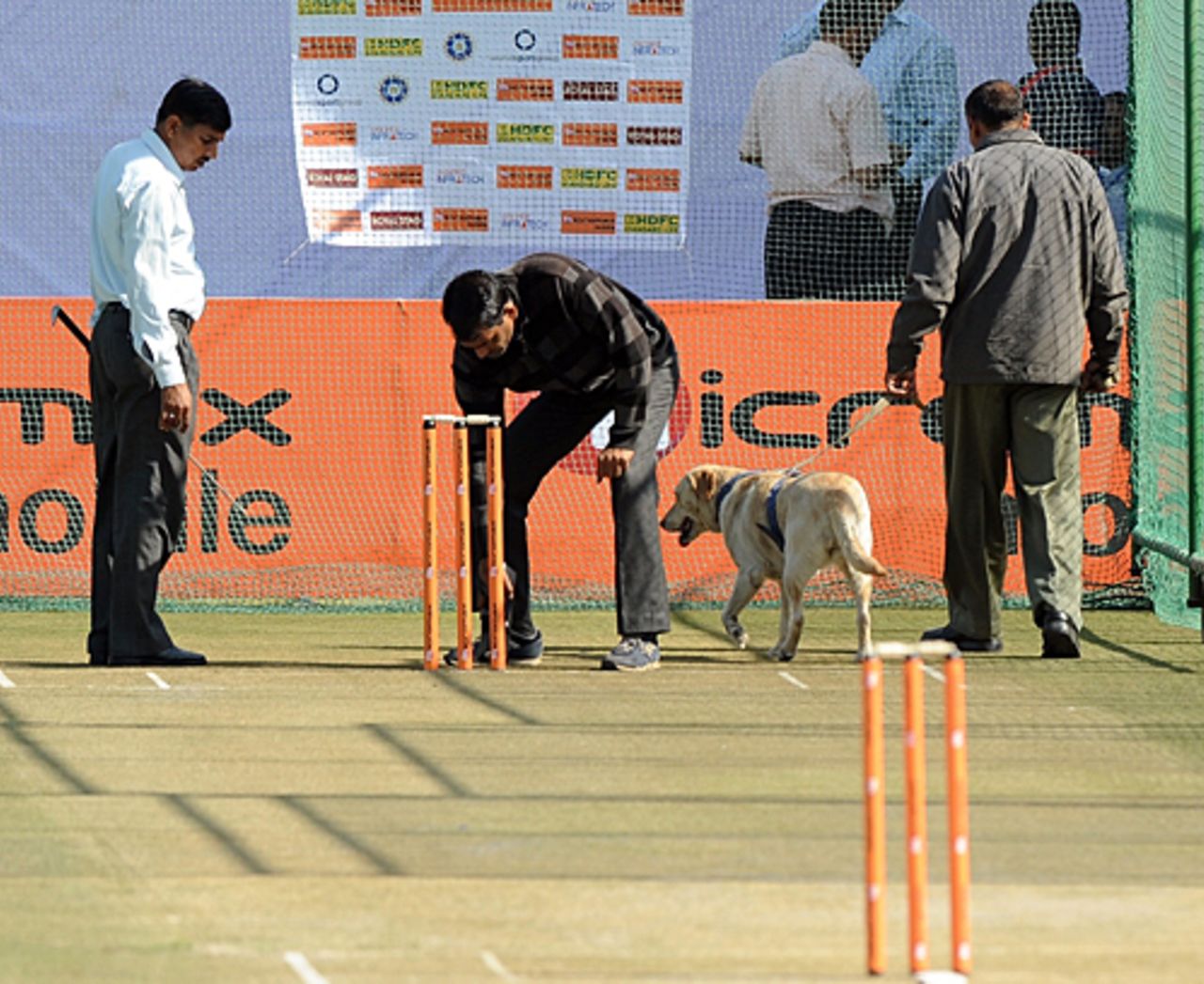 Indian security personnel and a sniffer dog check the nets prior to a training session, Jaipur, February 20, 2010