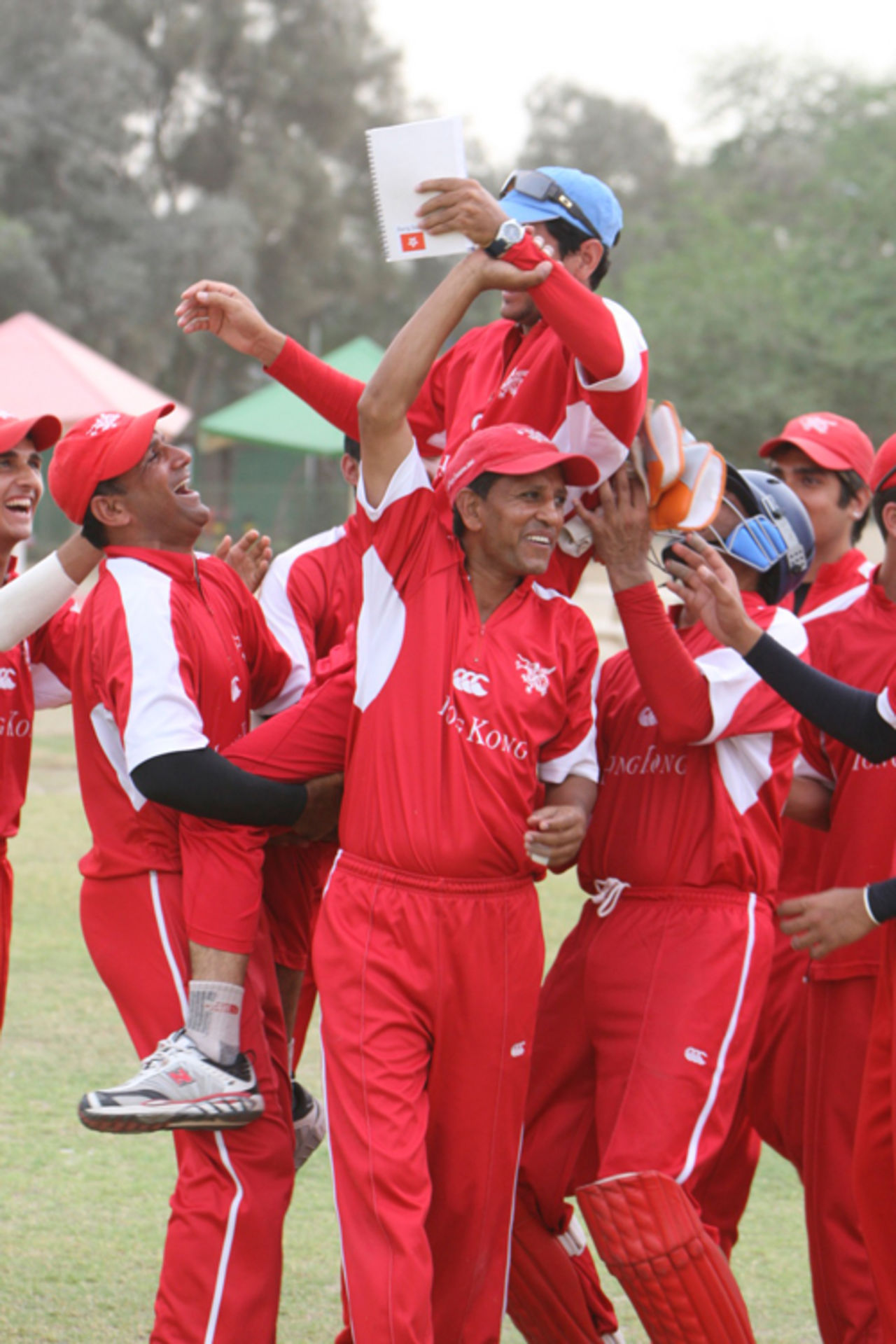 The Hong Kong players hoist coach Tabarak Dar in the air after beating Malaysia by 7 runs