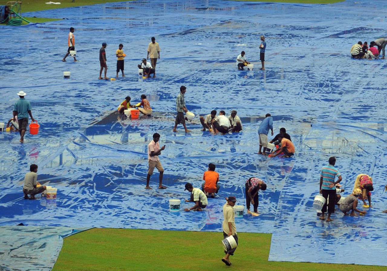 Groundstaff mop up the water on the covers at the Nehru Stadium in Margao, Margao, October 23, 2010