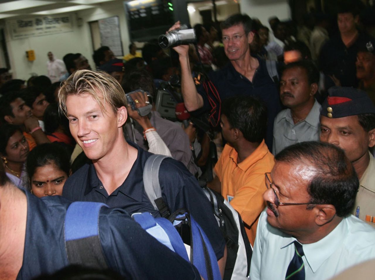 Brett Lee and John Buchanan walk through a crowd at the Nagpur airport, October 23, 2004