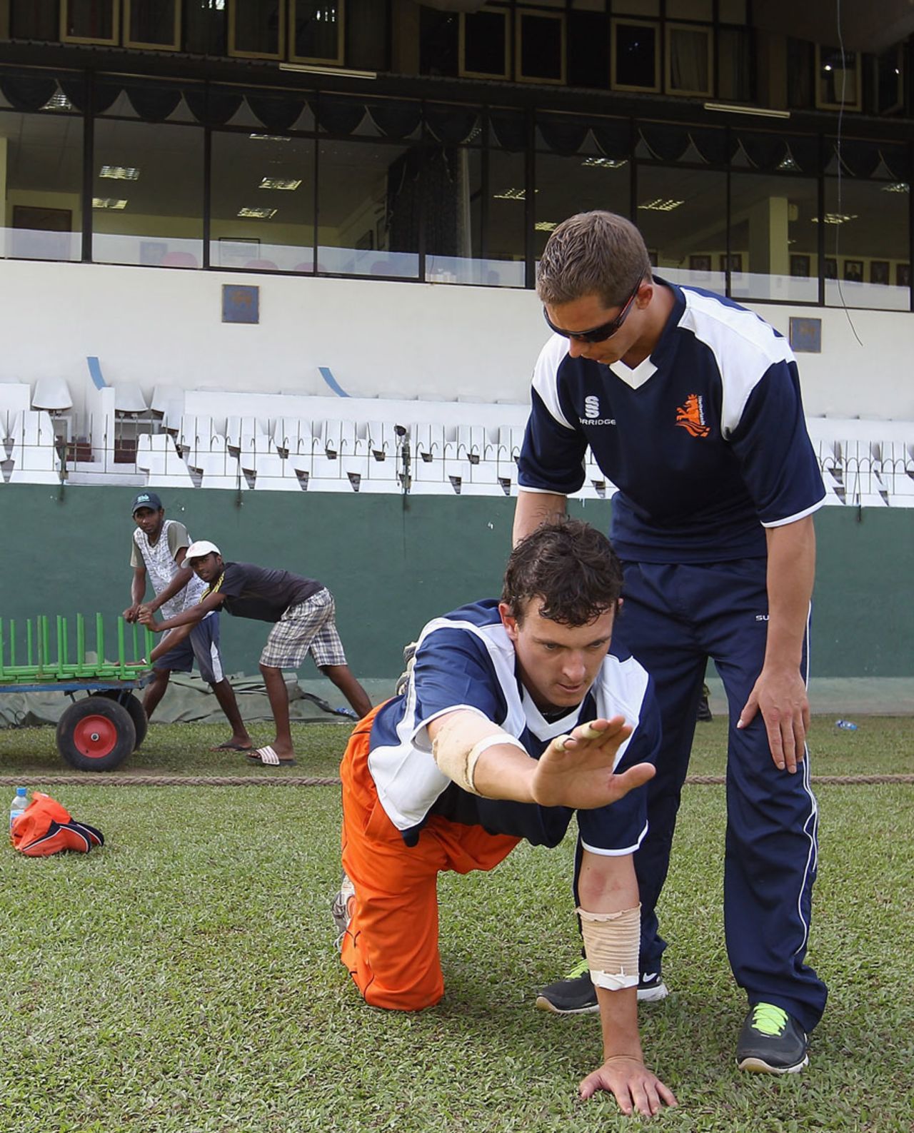 Netherland's Eric Szwarczynski stretches with the help of trainer Rowan Gravesteijn, Colombo, February 11, 2011