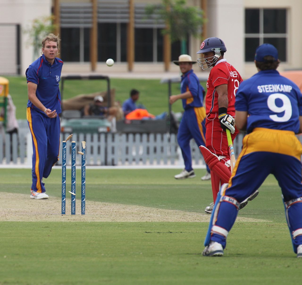 Namibia's Christi Viljoen fires the ball back at the stumps, breaking one of them against Hong Kong at the ICC WCL2 in Dubai on 14th April 2011