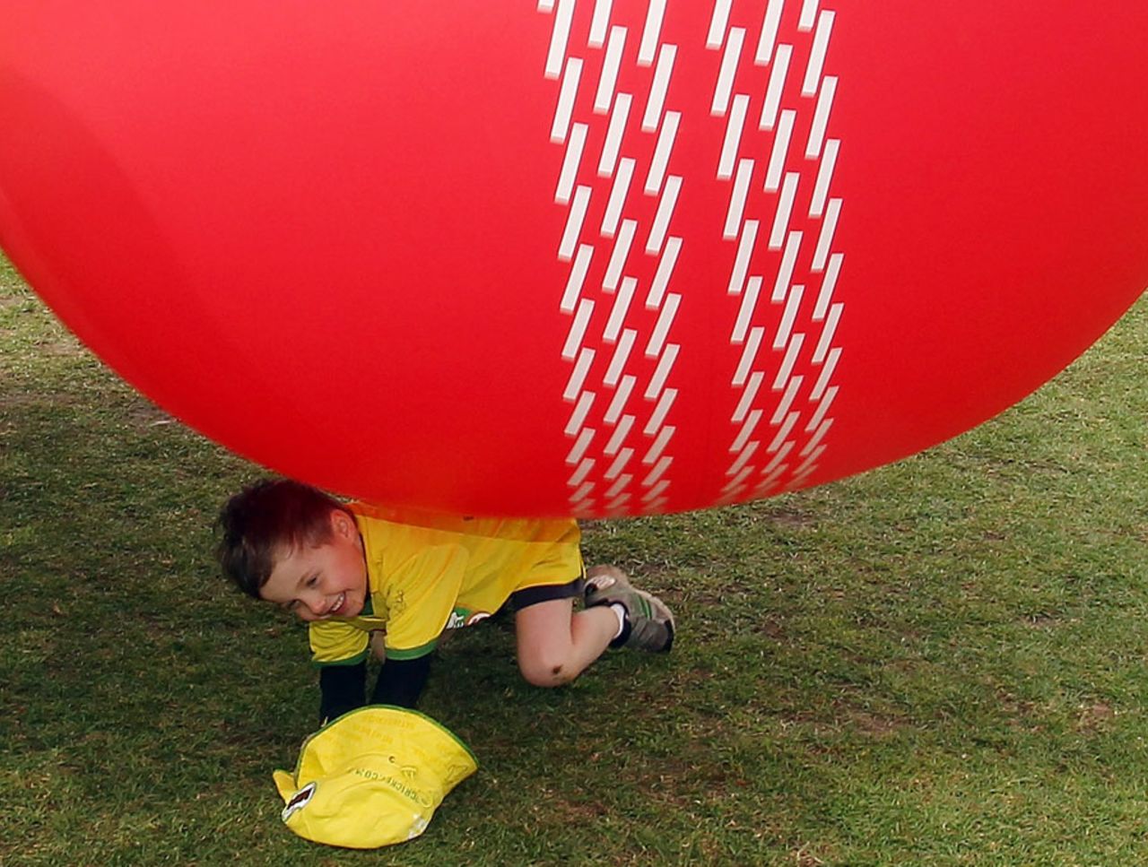 A giant cricket ball rolls on top of a young cricketer during the MILO in2Cricket Launch, Sydney, October 5, 2011