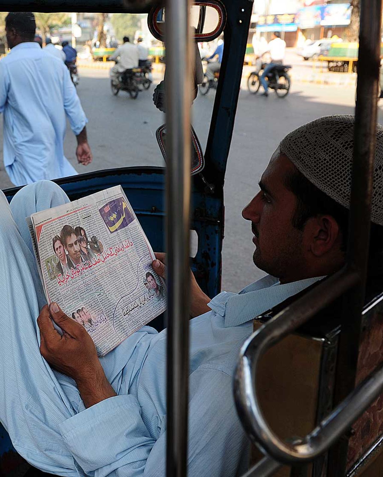 An autorickshaw driver reads about the spot-fixing convictions in an Urdu newspaper, Karachi, November 4, 2011