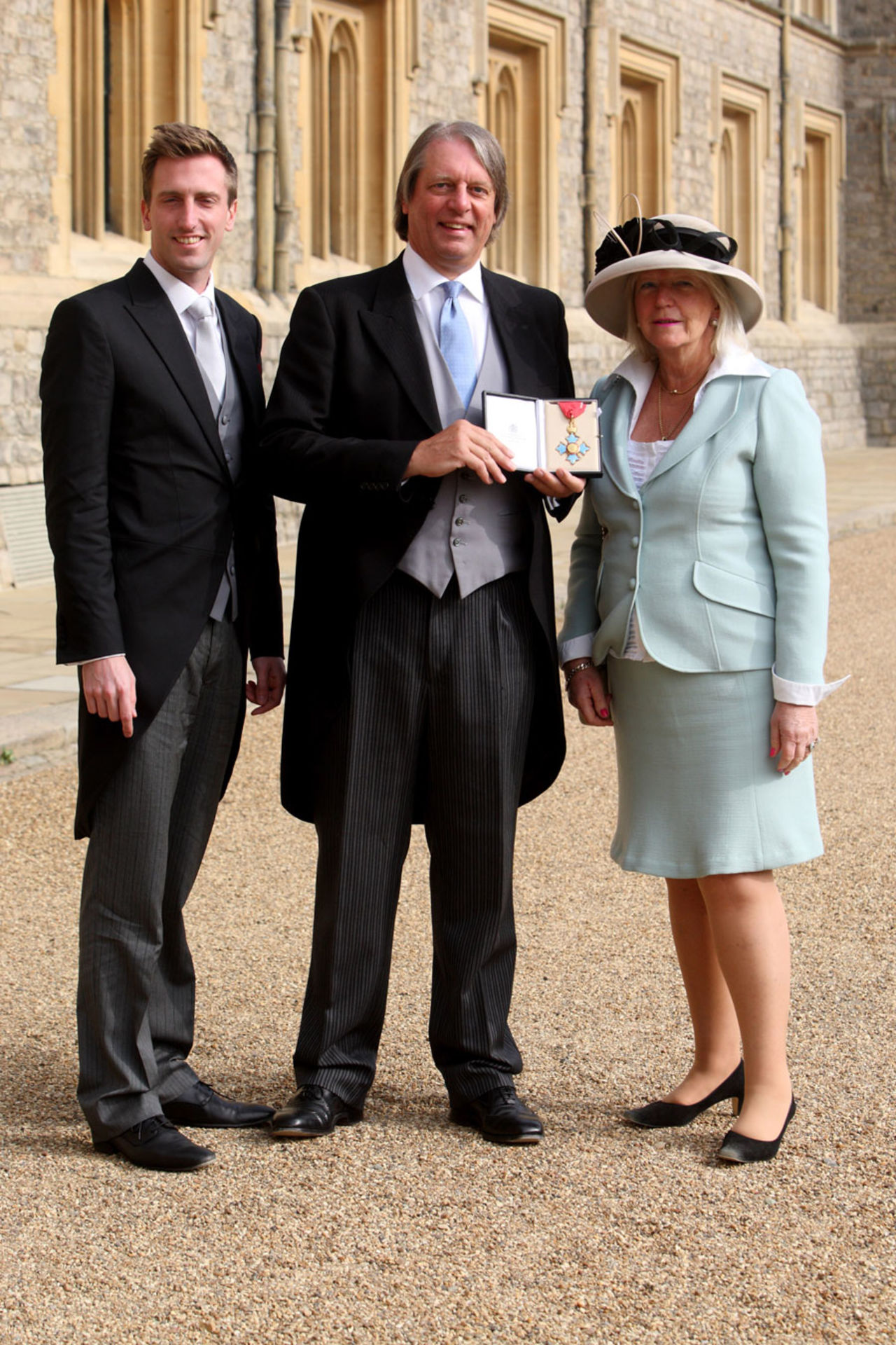 ECB head Giles Clarke, with his wife Judy and son Jack, poses with his CBE that was presented by Queen Elizabeth II, Windsor, March 2, 2012