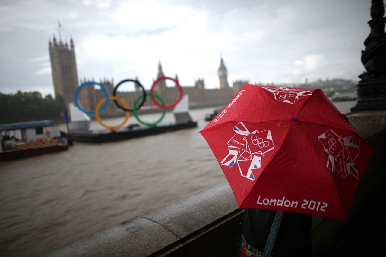 A tourist looks at the giant Olympic rings on the Thames, London, August 5, 2012