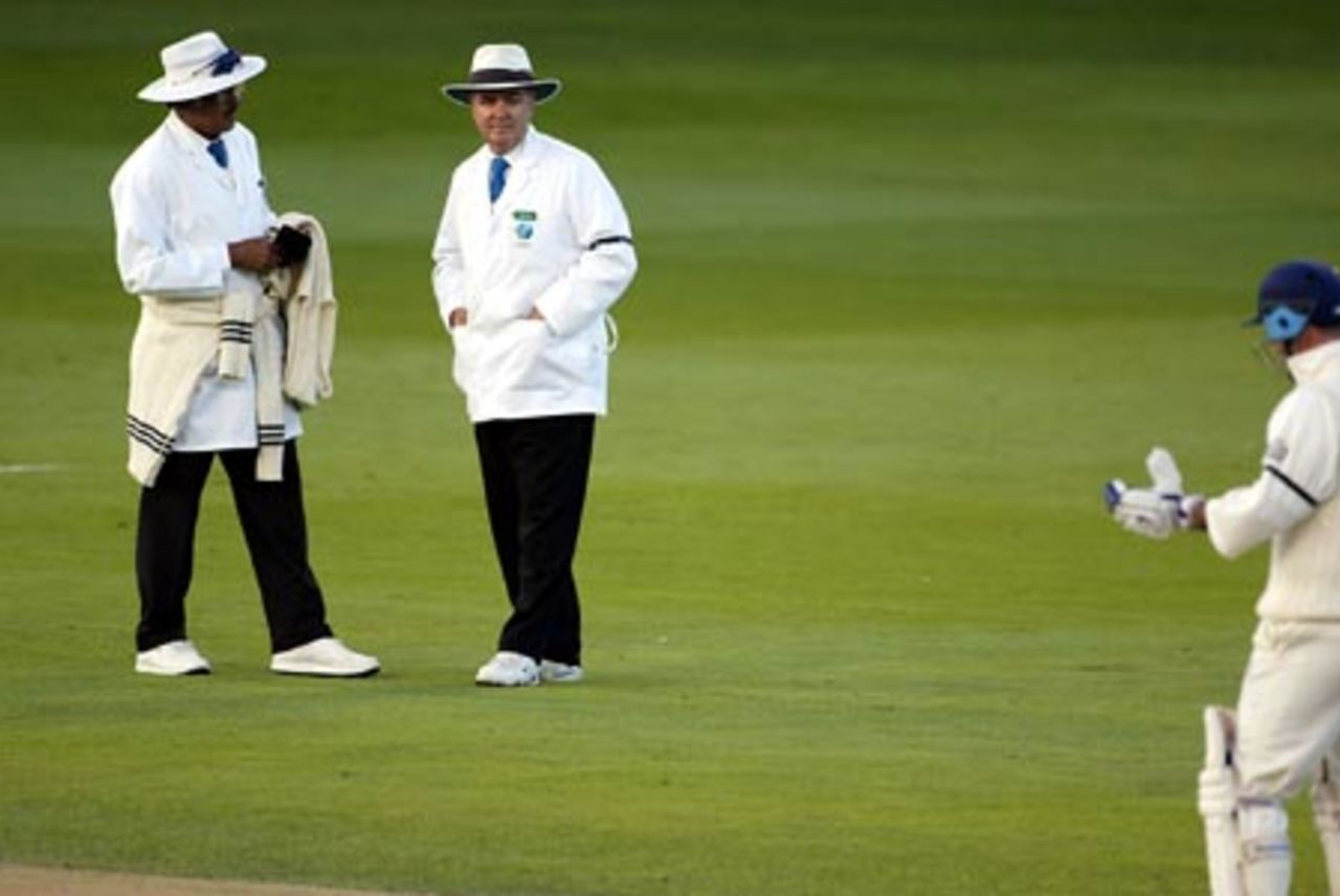 Umpires Srinavas Venkataraghavan (left) from India and Doug Cowie offer the light to the England batsmen. The offer was accepted and the third day's play ended. Graham Thorpe (right) walks from the field. 3rd Test: New Zealand v England at Eden Park, Auckland, 30 March-3 April 2002 (1 April 2002).