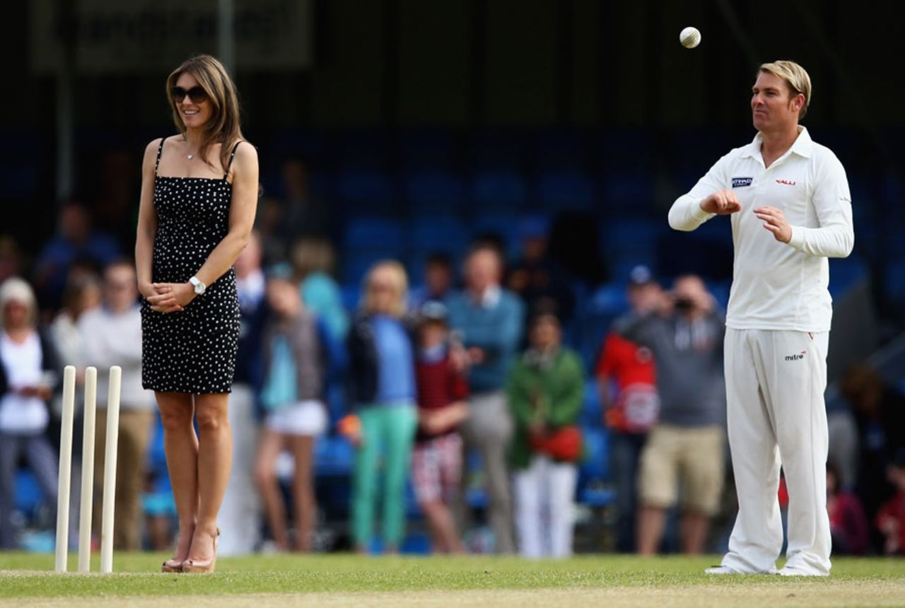 Shane Warne prepares to bowl with wife Liz Hurley umpiring, Cirencester, June, 9, 2013