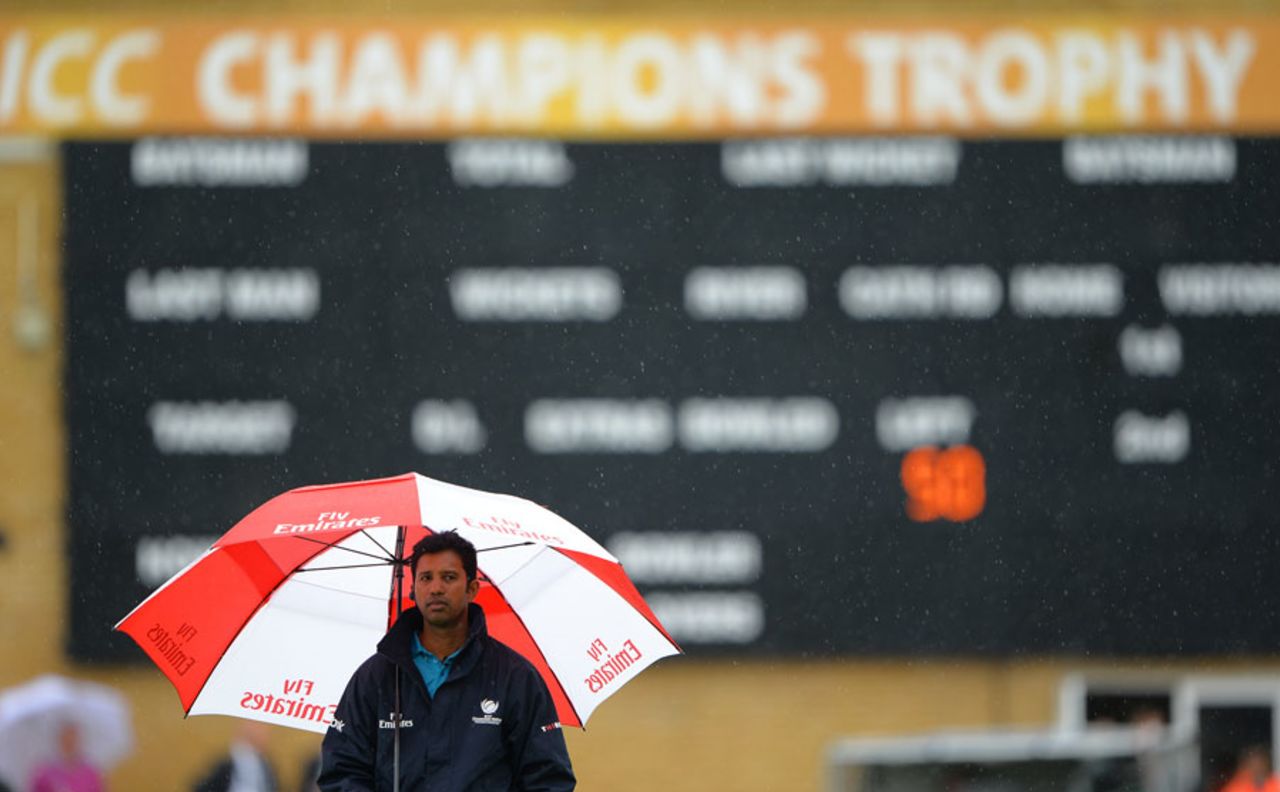 Kumar Dharmasena takes cover from the deluge, England v New Zealand, Champions Trophy, Group A, Cardiff, June 16, 2013