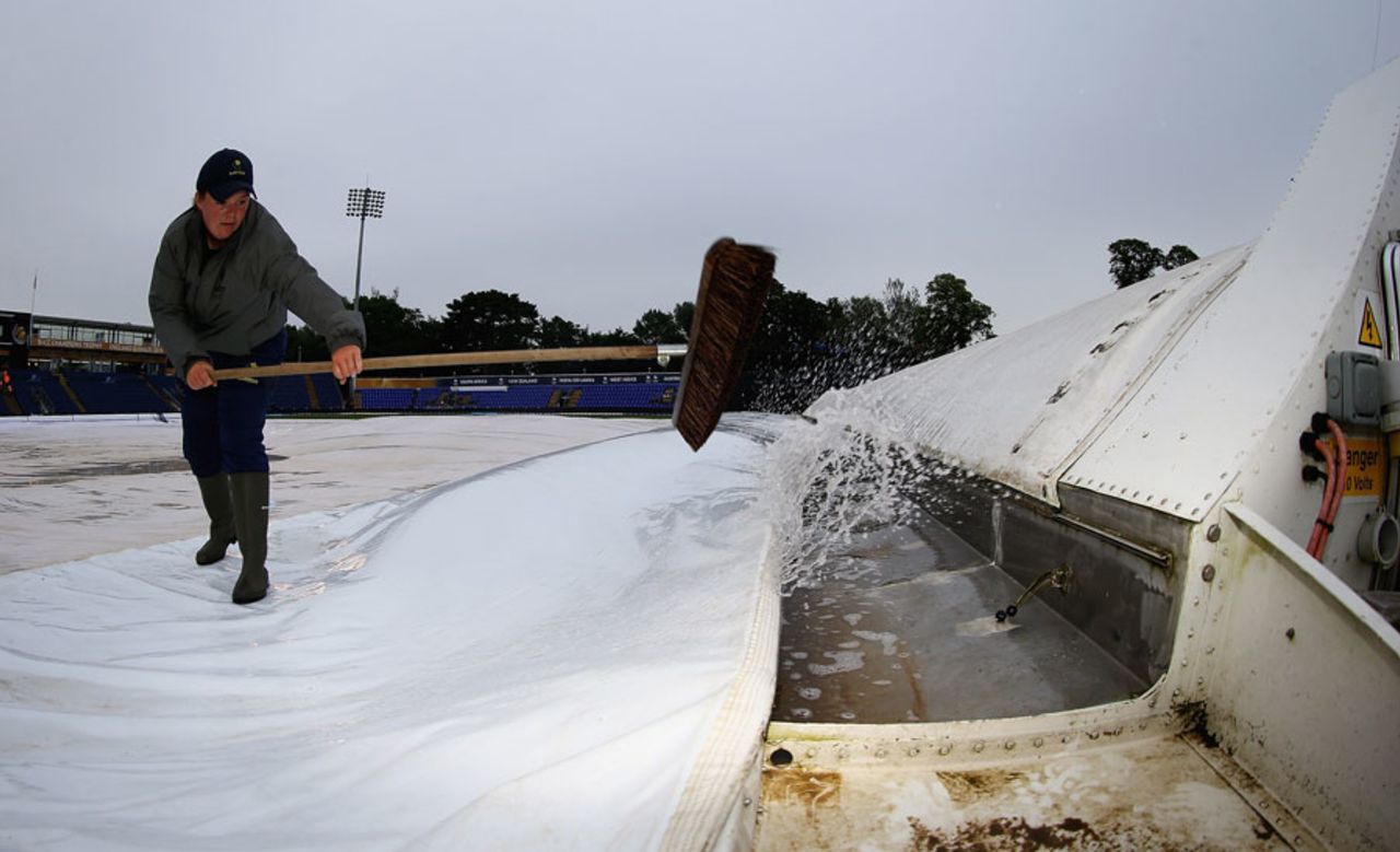 A member of the ground staff clears water from the covers, India v Sri Lanka, Champions Trophy, 2nd semi-final, Cardiff, June 20, 2013