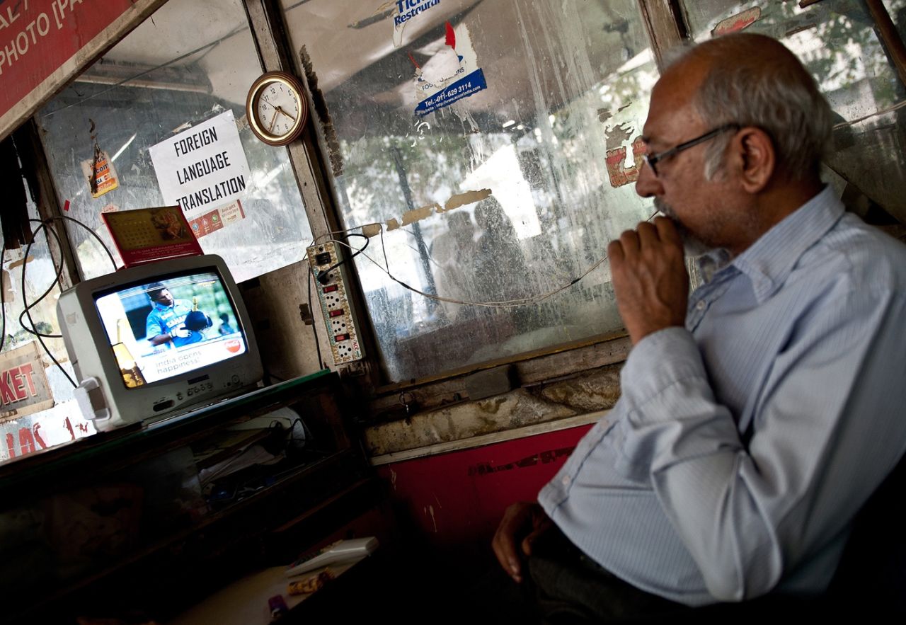 A shopkeeper watches Sachin Tendulkar bat, Delhi, March 16, 2012