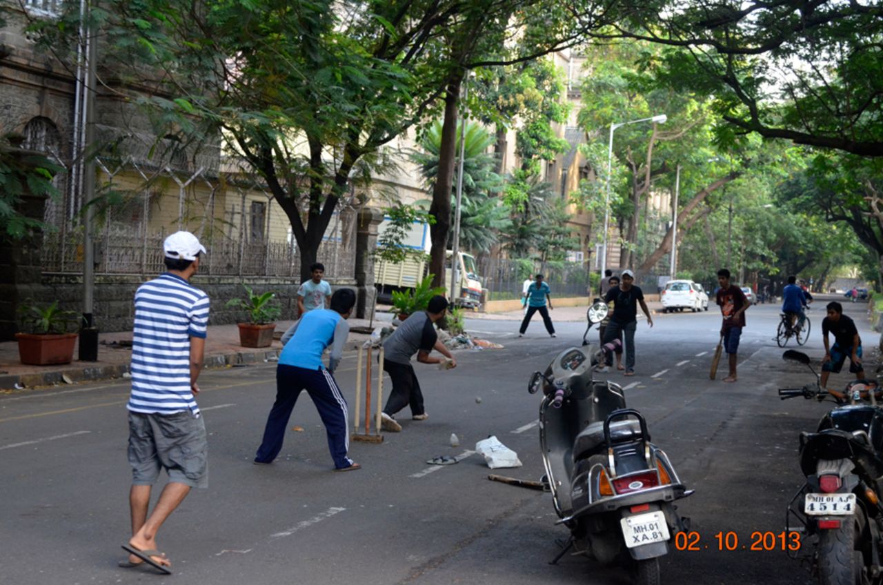 An impromptu game of cricket underway near the Gateway of India in Mumbai, on the anniversary of Mahatma Gandhi's birthday. The bowling captain seems to have done his best to plug the holes in his field with his team-mates' rides